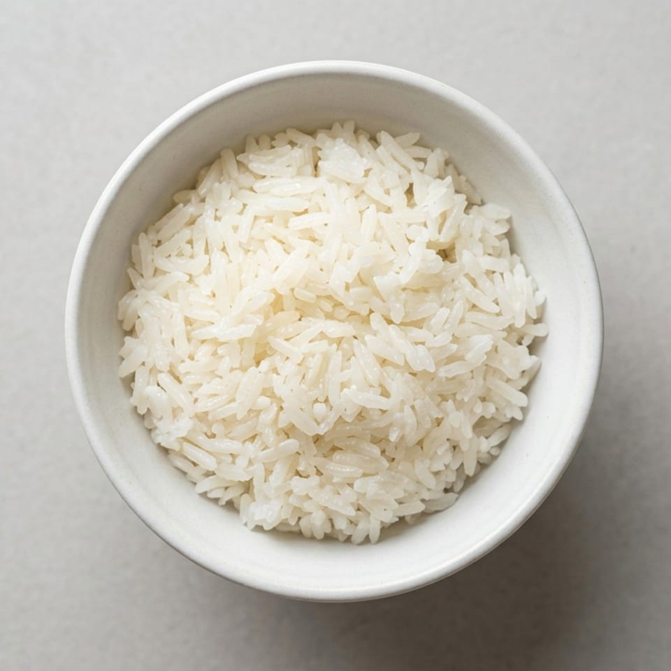 Overhead view of a white bowl filled with steamed white rice on a gray tabletop.