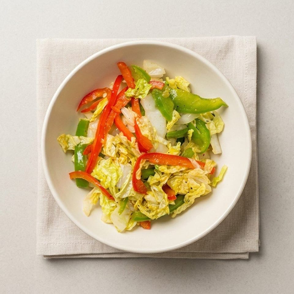 Bowl of mixed green and red peppers, cabbage, and lettuce served on a white plate over a folded napkin.